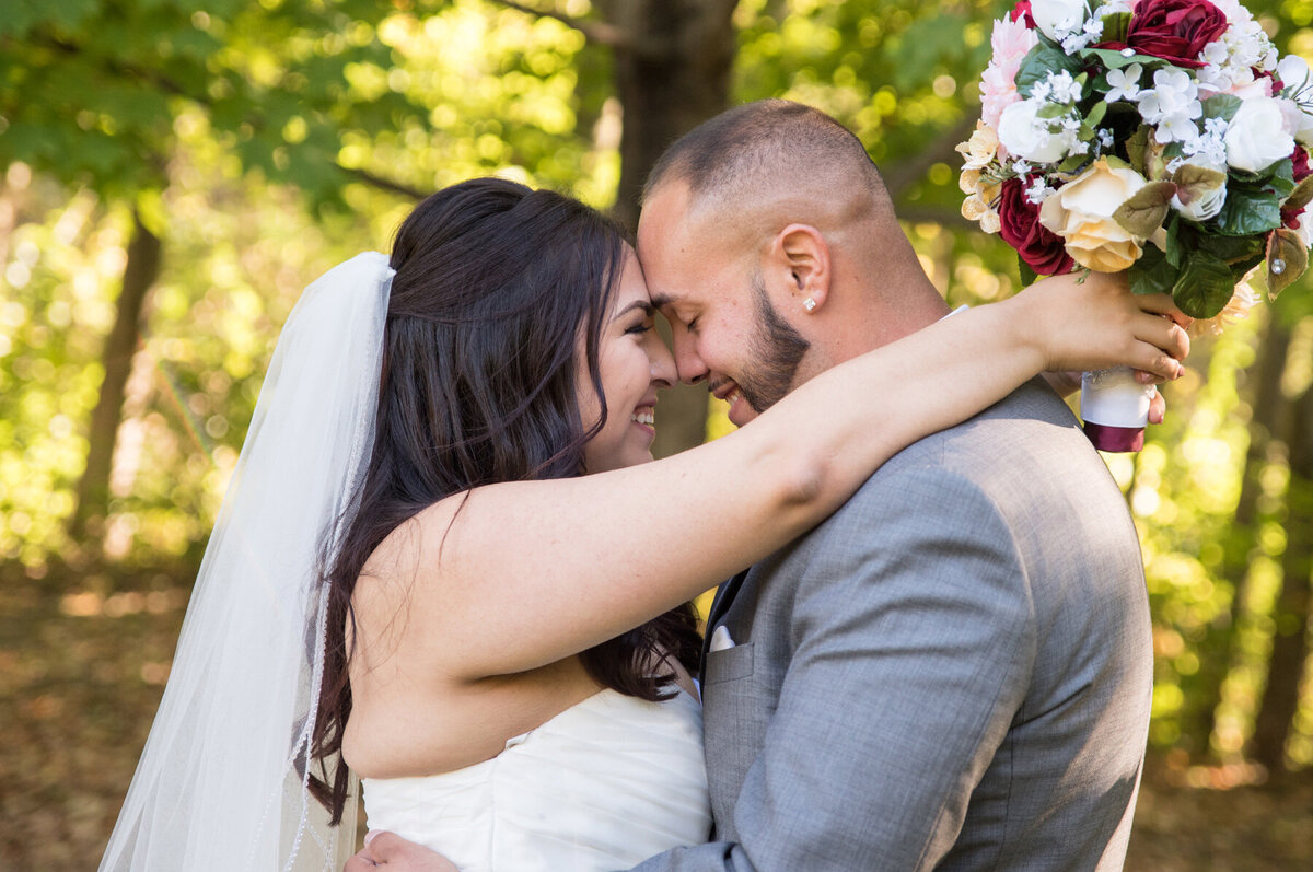 Bride and groom embrace outdoors and smile on their wedding day