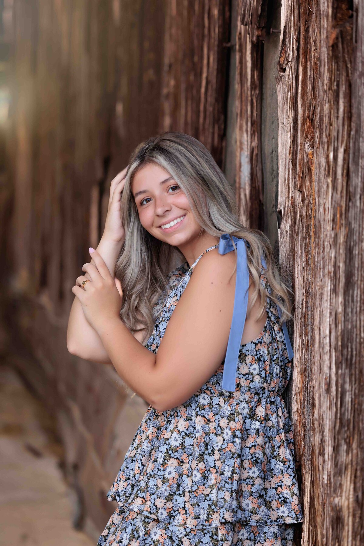 Raleigh high school senior standing by a rustic barn for senior photographs.