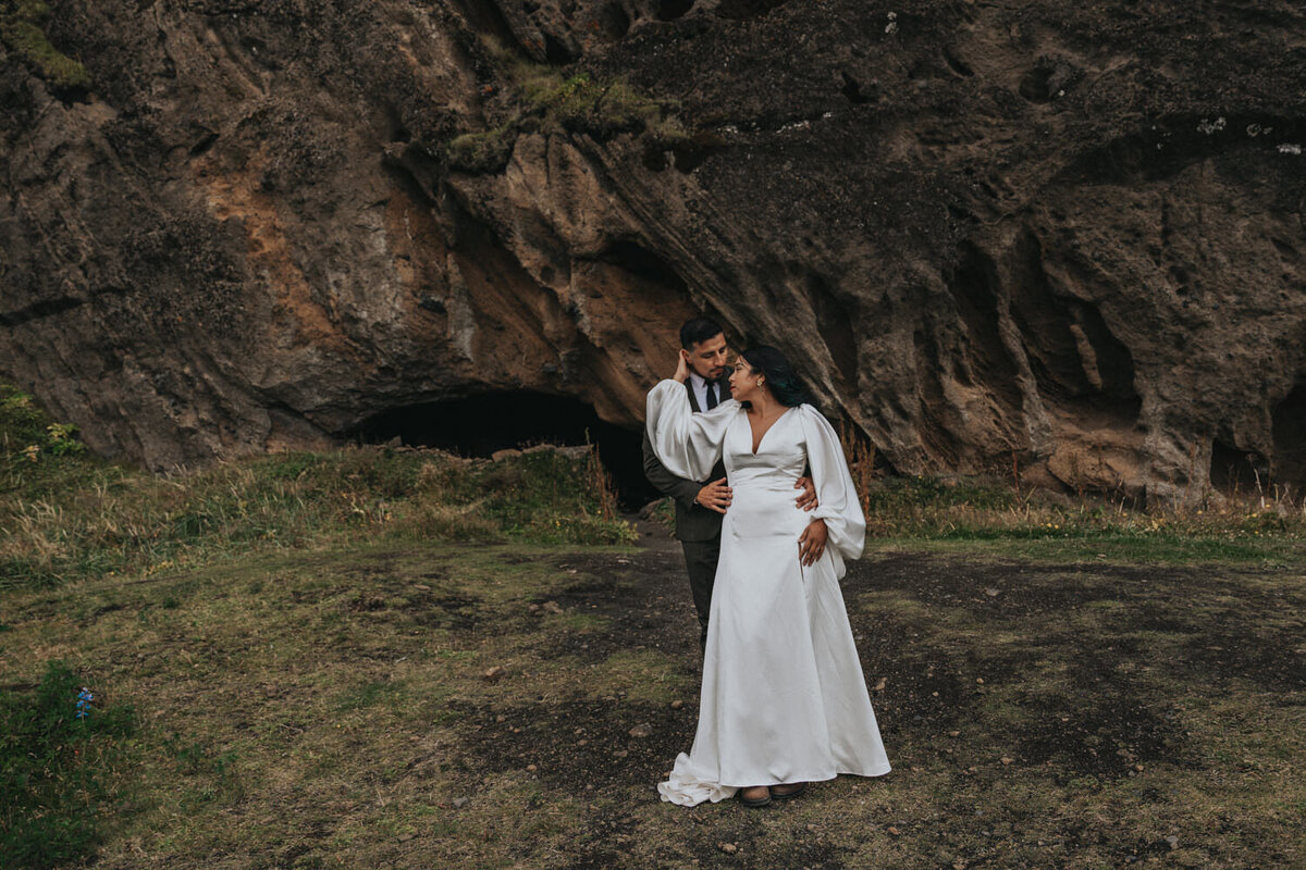 In a quiet, intimate moment, a husband and wife kiss near a secluded waterfall