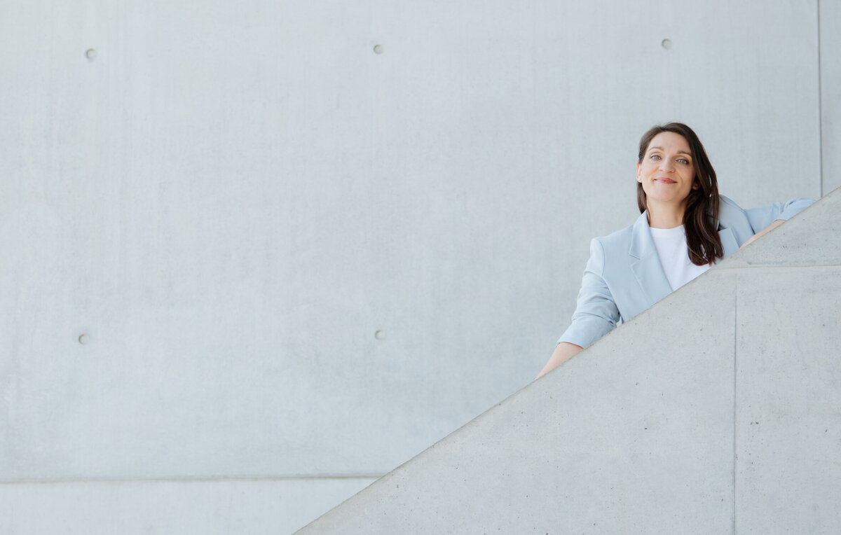 Stephanie Bretz – Detailaufnahme, minimalistisches Porträt mit architektonischem Setting auf Treppe.