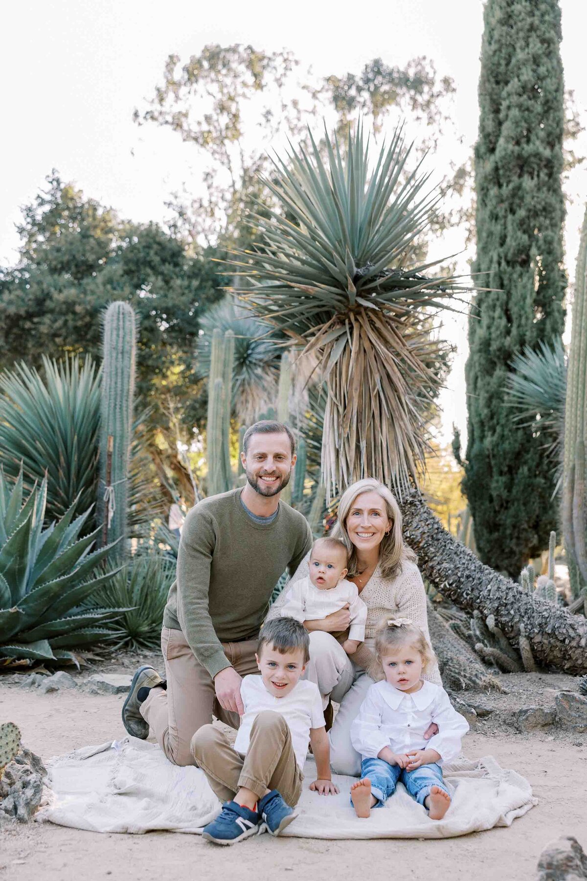 family of 5 sitting and smiling at arizona cactus garden
