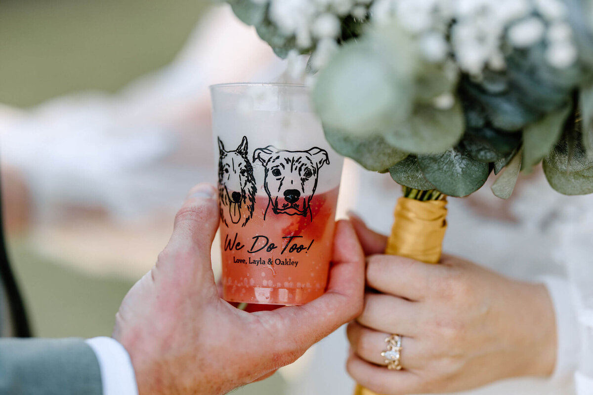 bride and groom holing customized cocktail glass with fur babies on glass