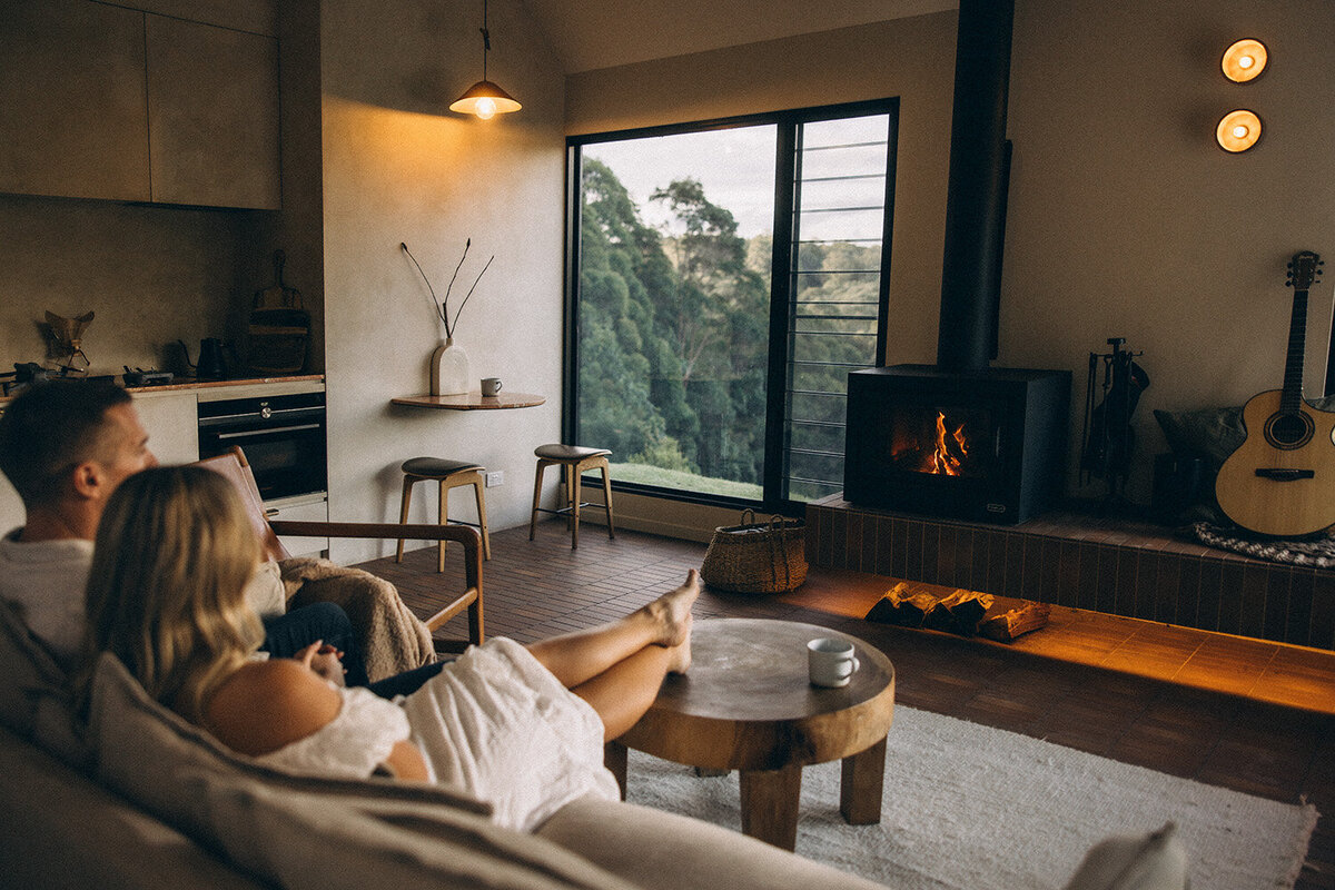 Cosy couple on the lounge in front of a fire place in a Noosa Hinterland AirBNB. Captured by Sunshine Coast Photographer