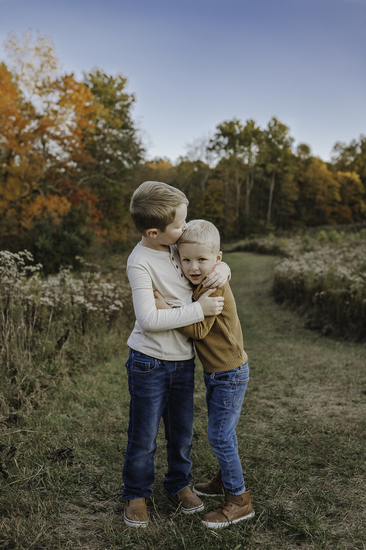 Verona B Photography captures a beautiful fall family photo of two brothers hugging and kissing each other at Kendall Hills in Peninsula, OH. Brothers are friends for a lifetime! The fall colors were really at peak color and the sun was perfect for this family photo session near Akron.
