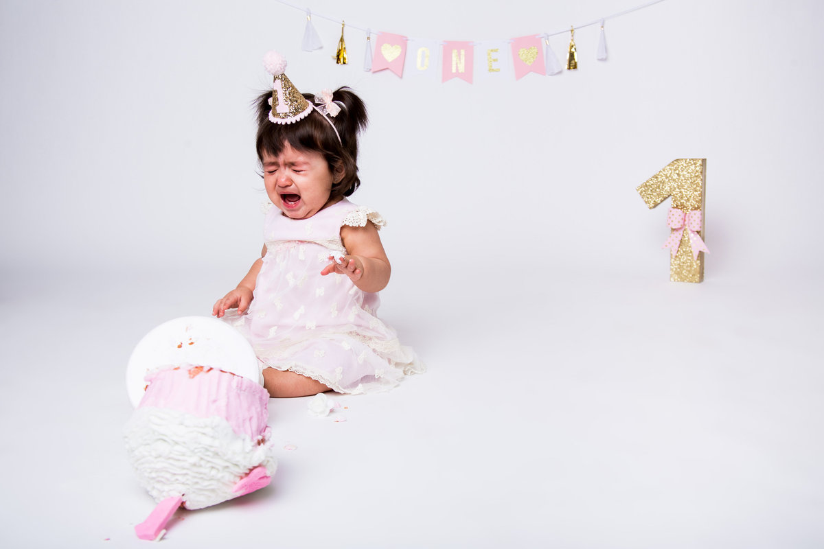 Cake smash with baby crying over cake that has fallen over in Expose The Heart Studio