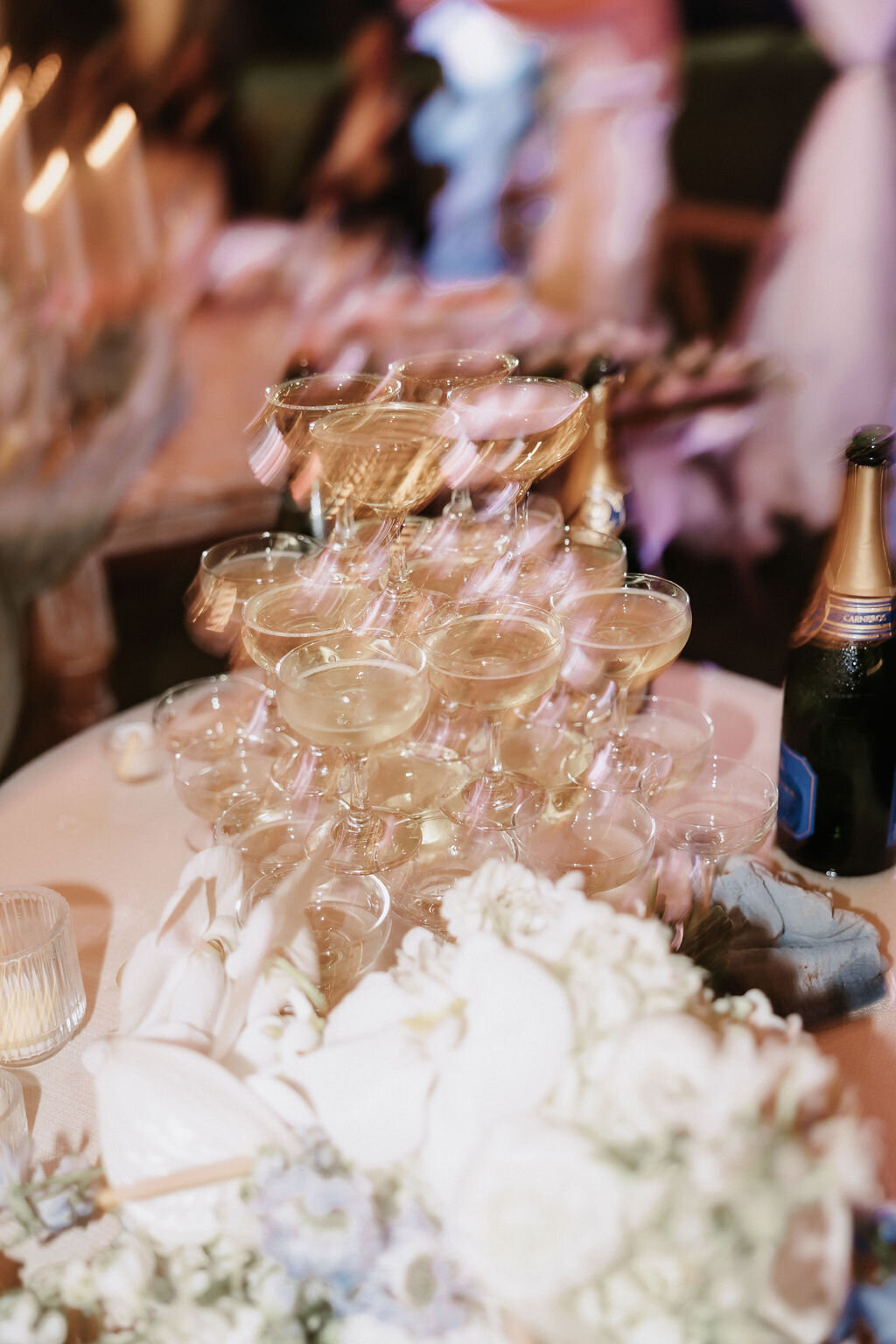 blurry aesthetic image of champagne tower after the champagne pour at wedding guest candid photo under clear tent at lanikuhonua