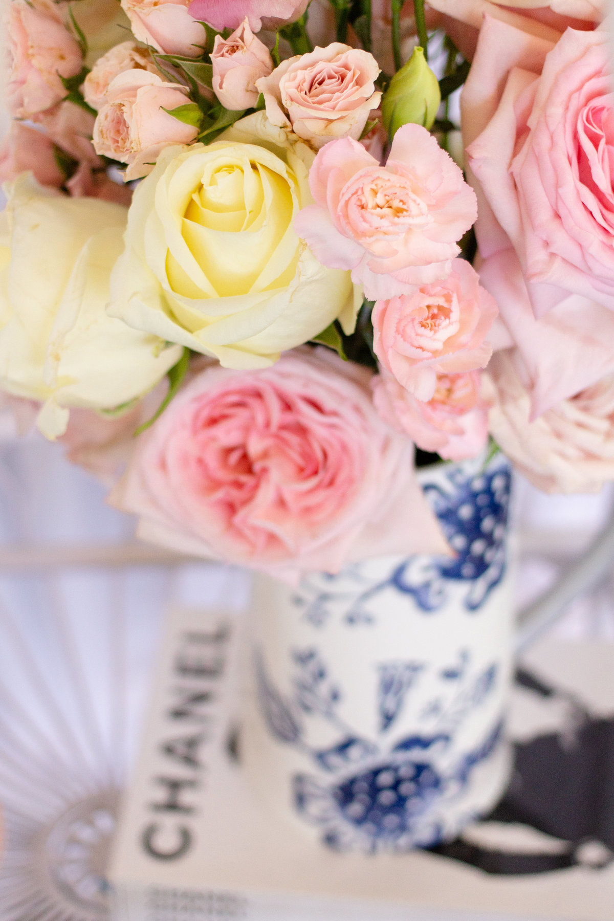 Pink and yellow wedding centerpiece bouquet in white and blue vase on top of Chanel magazine at wedding reception in Tampa, Florida