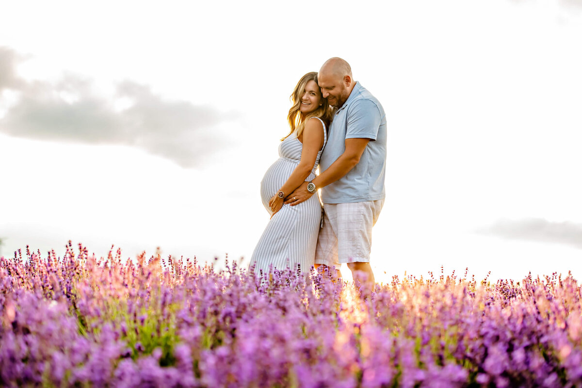 husband and wife hugging with the sunsetting behind in the lavender field for their Toronto maternity photography session