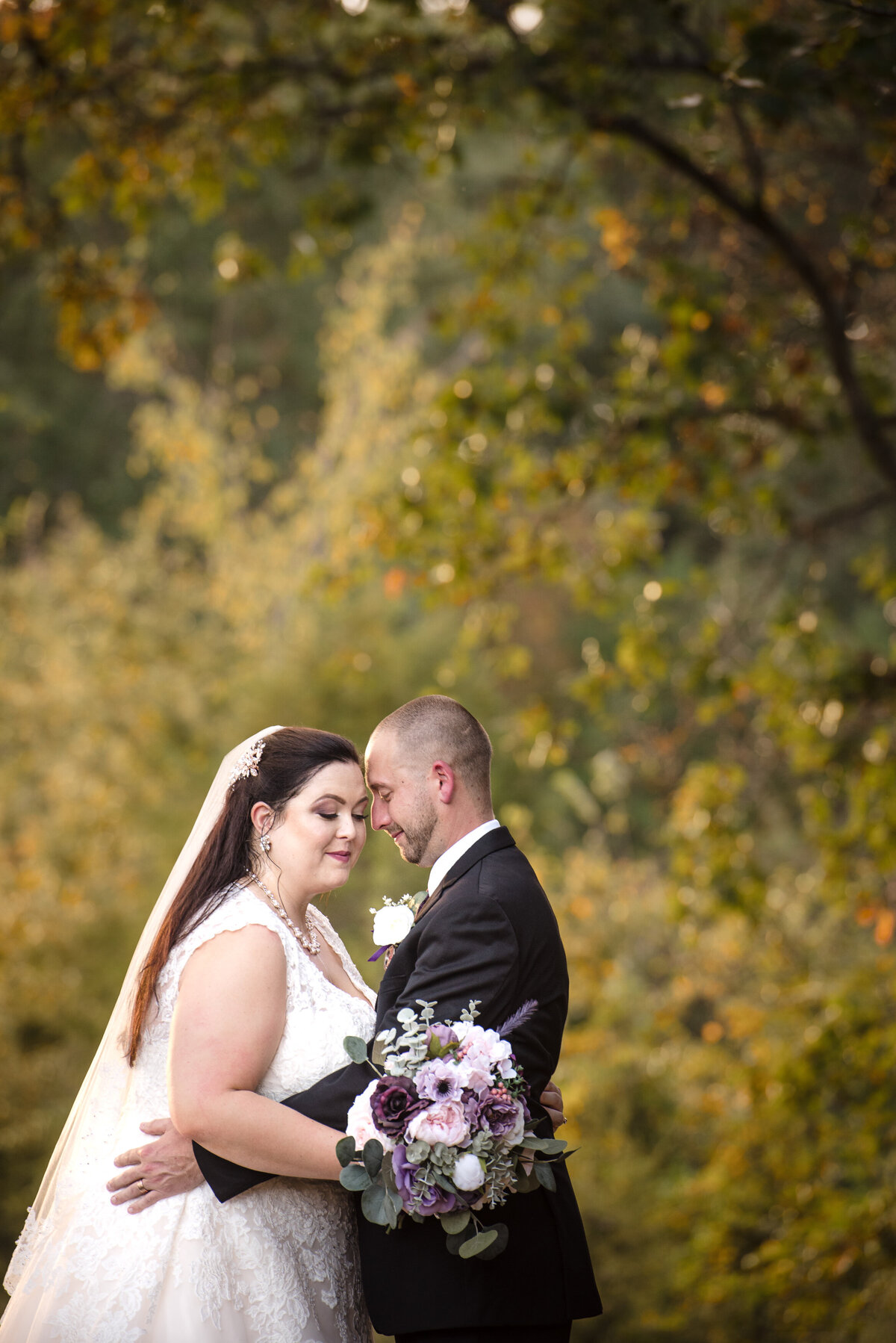 Bride and groom nuzzle foreheads with eyes closed outside at Rolling Hills Farm