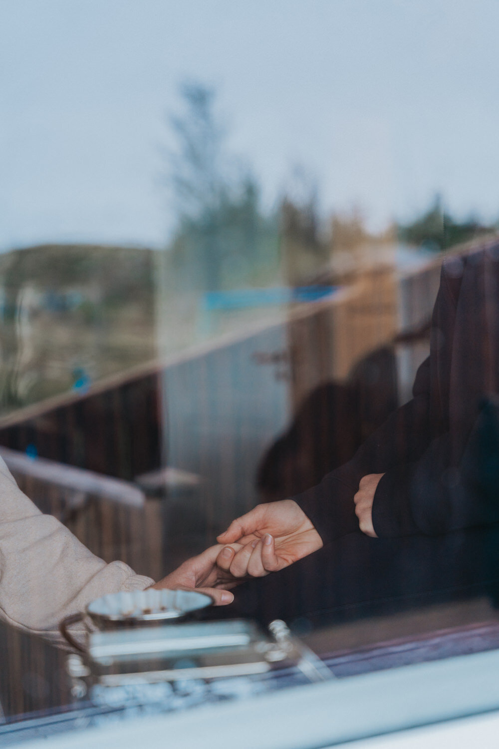 Women hold hands near the window of an Icelandic cottage 