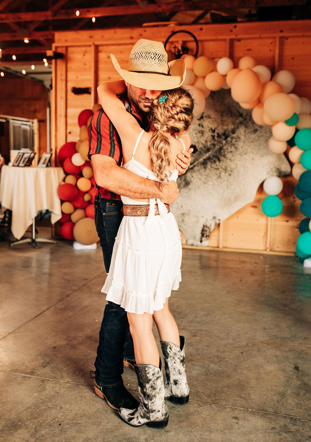 bride and groom embracing in front of balloon arch