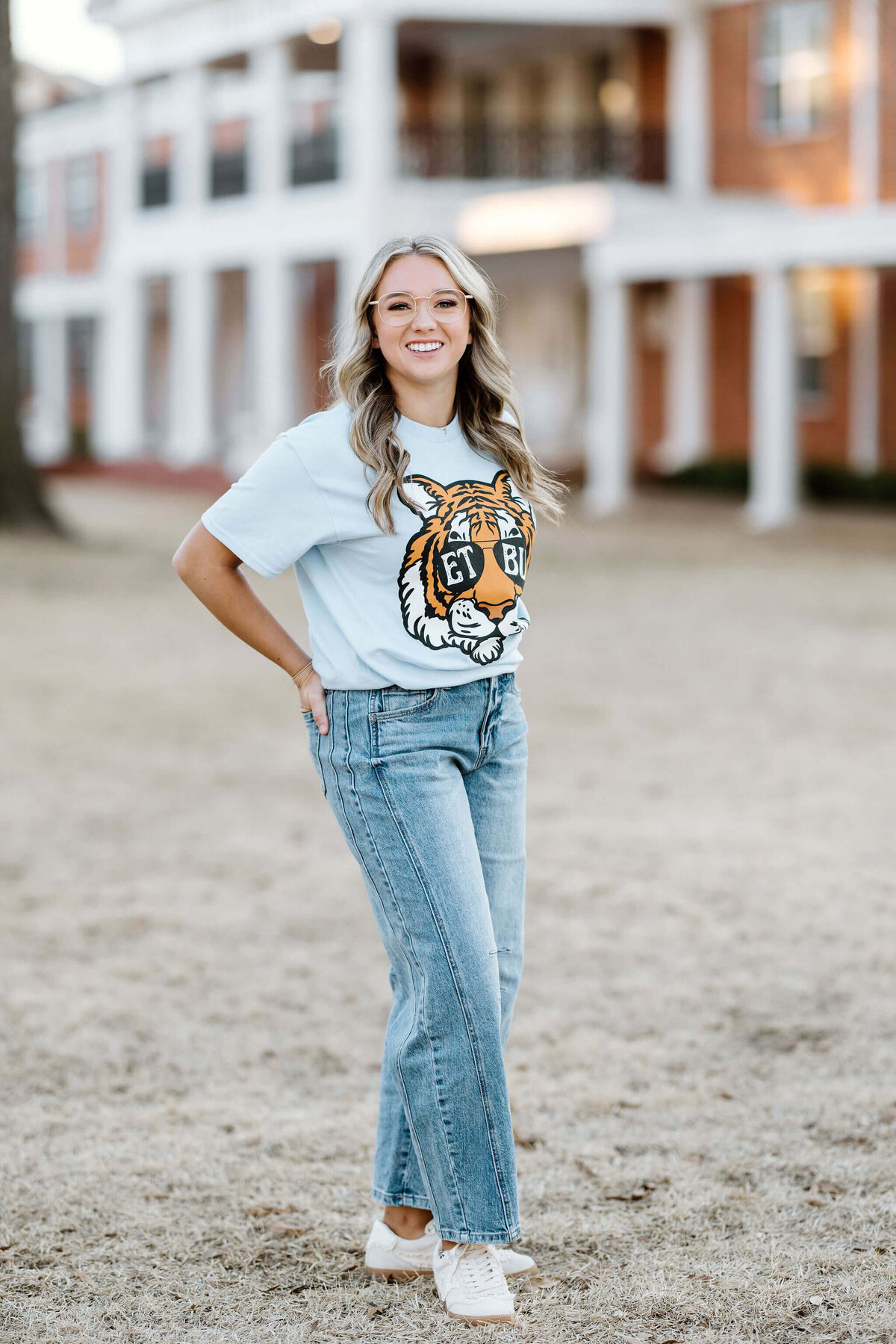 ETBU graduate wearing college graphic teeshirt and jeans standing on college campus