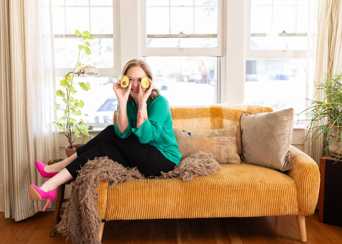 Portland branding photographer session with female sitting on couch with avocados over her eyes. 