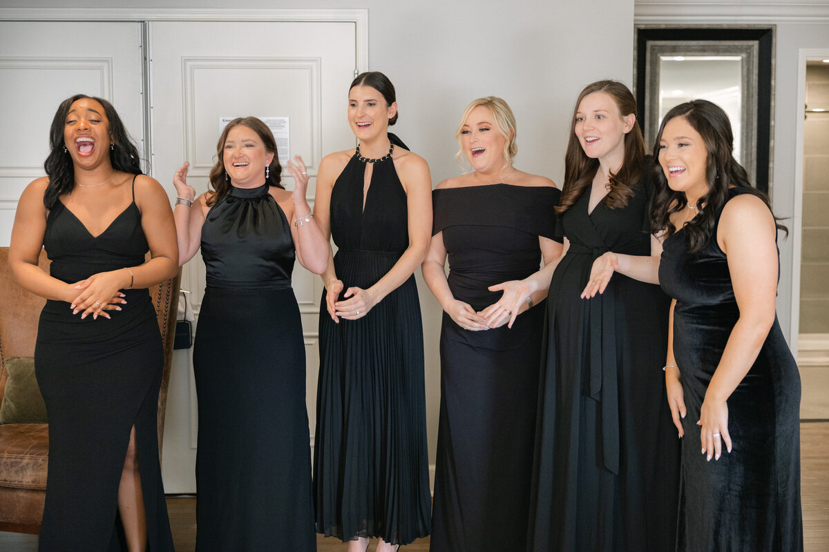 bridesmaids in black dresses reacting during the bride’s first look at The Adolphus in Dallas, capturing joyful and heartfelt wedding moments at the venue.