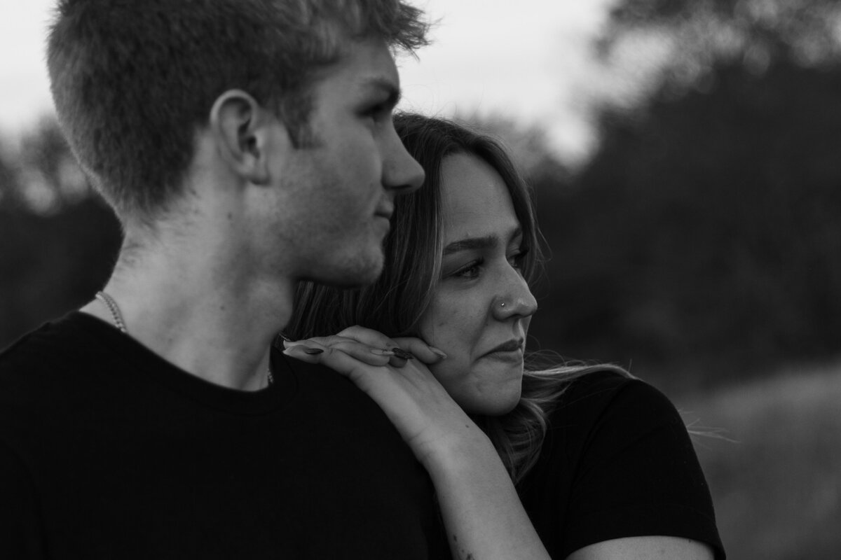Girlfriend leaning into boyfriend in a black and white photo for their engagement pictures 