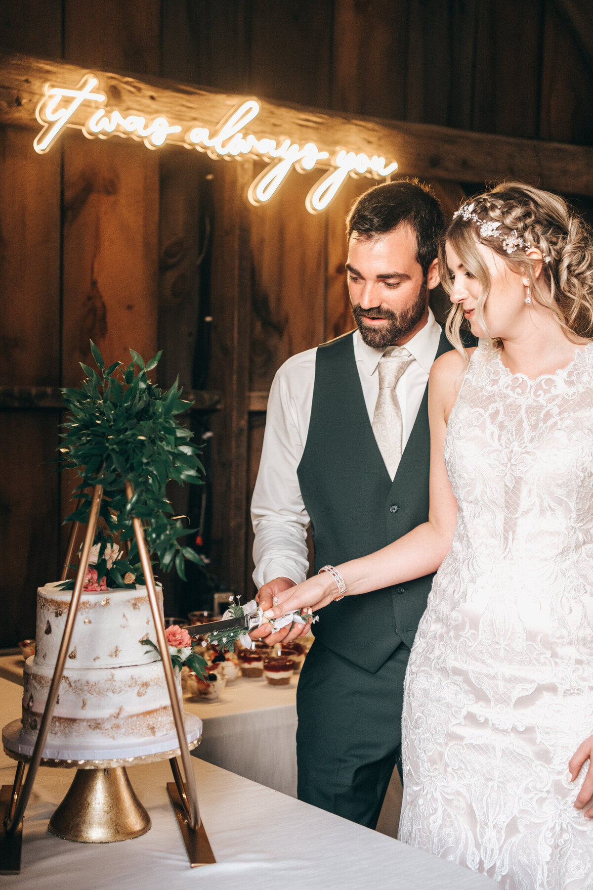A bride and groom cutting the cake during their rustic, chic barn wedding