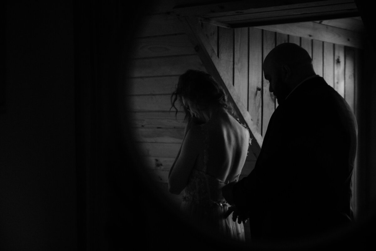 black and white image of groom helping bride in the mirrror