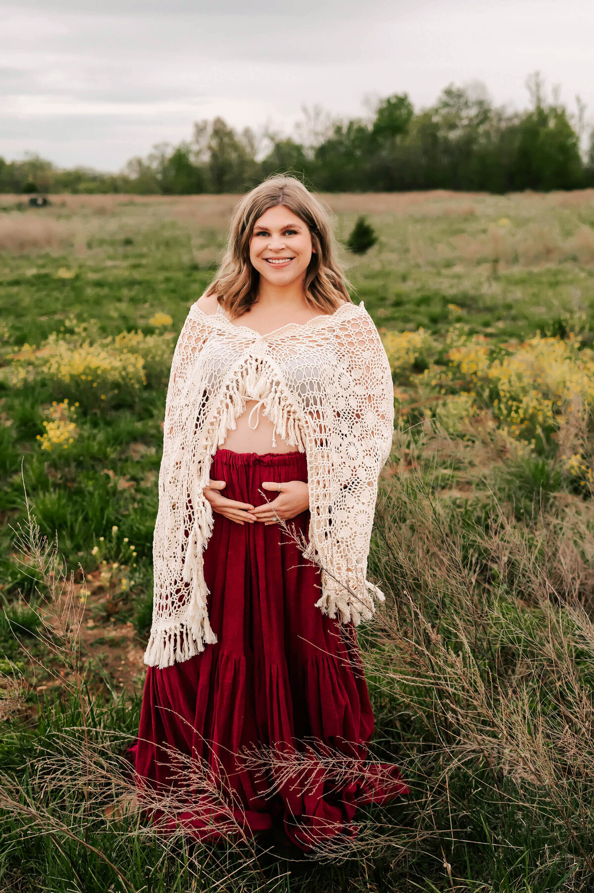maternity photo of pregnant mom in crochet shirt smiling in a field in Springfield MO