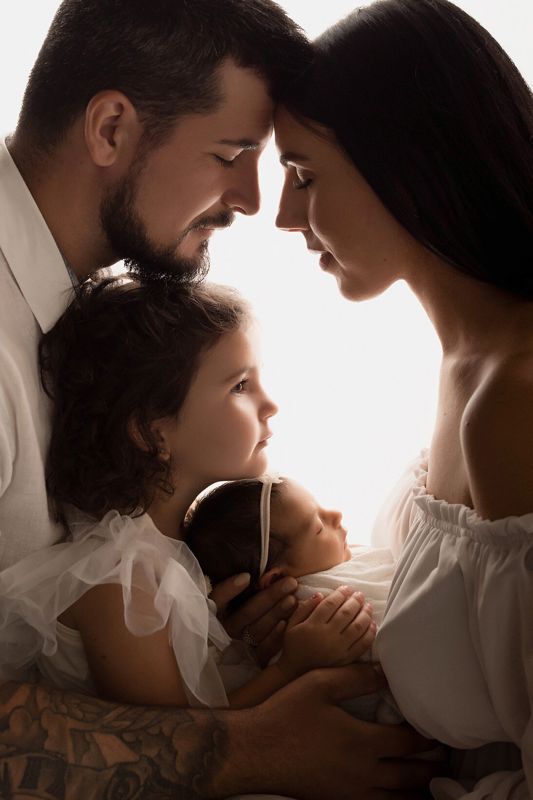 backlit family portrait in white with newborn
