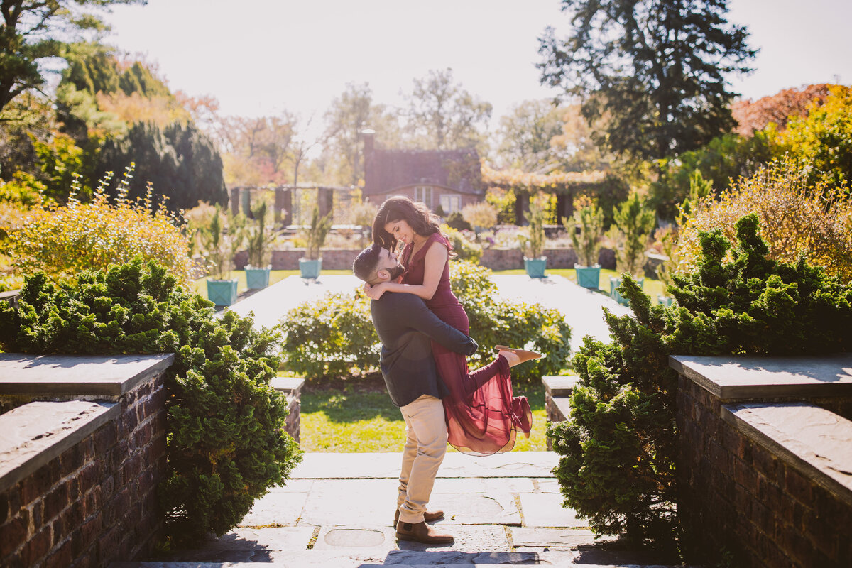 Groom picking up the bride during their engagement session at planting fields arboretum in long island ny