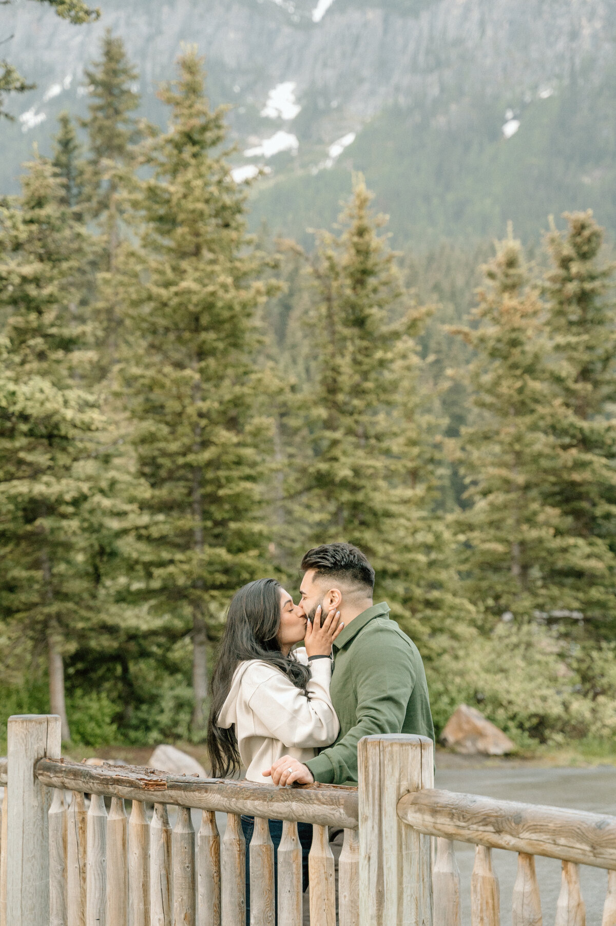 Woman kissing her fiancee passionately after being proposed to in Lake Louise at sunrise. 