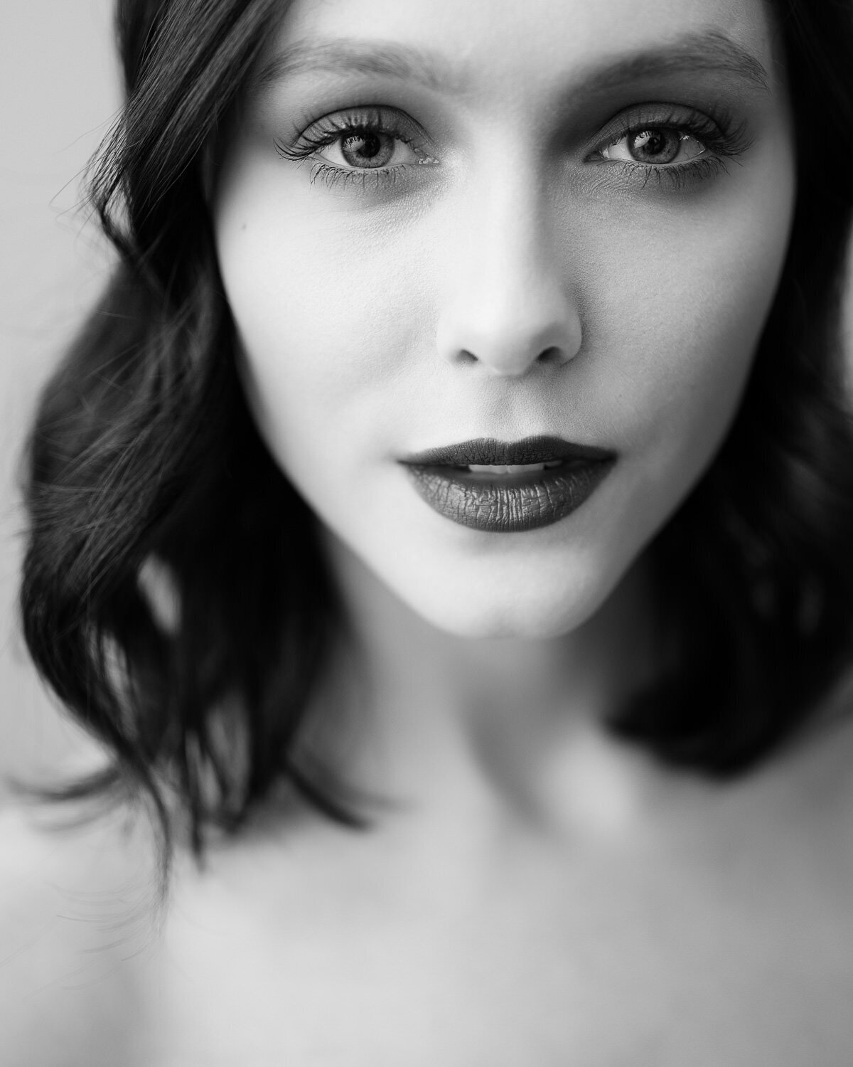 Close-up editorial portrait of a woman with soft side lighting, highlighting natural features and elegant expression.