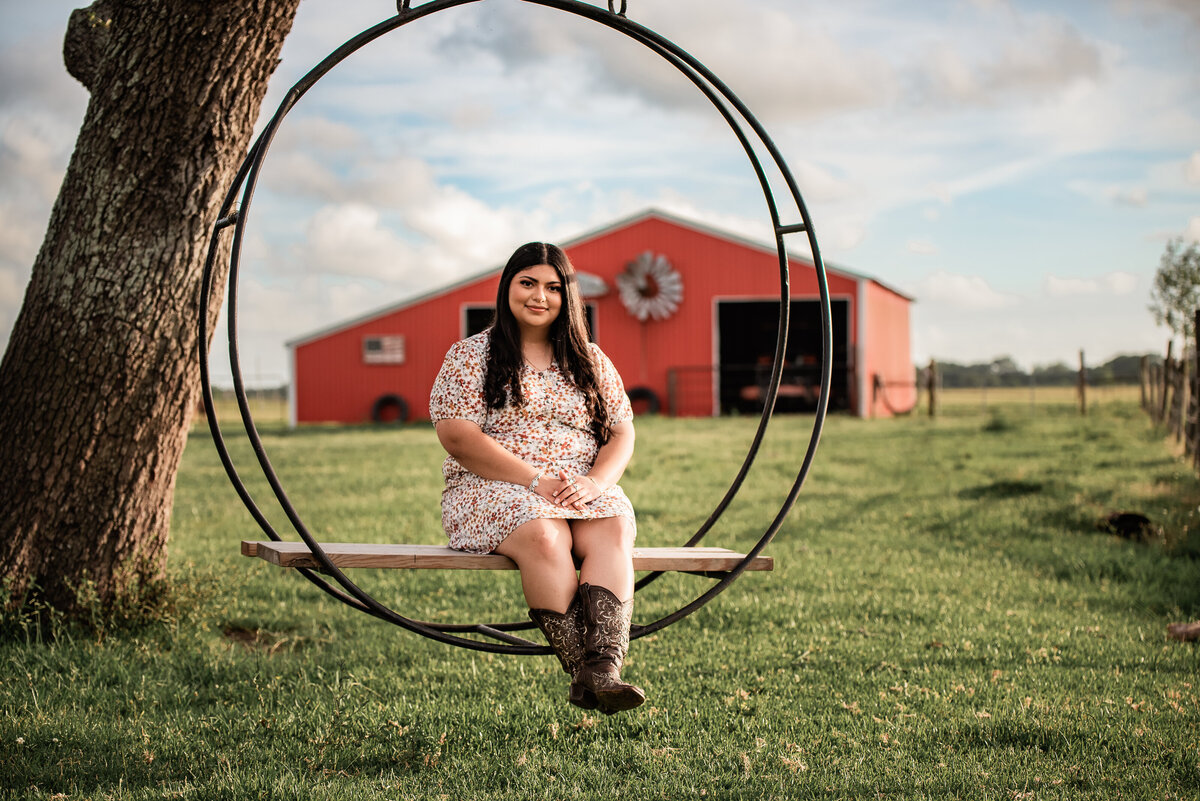 A  senior sits on a round circle swing at a farm in Galveston county.