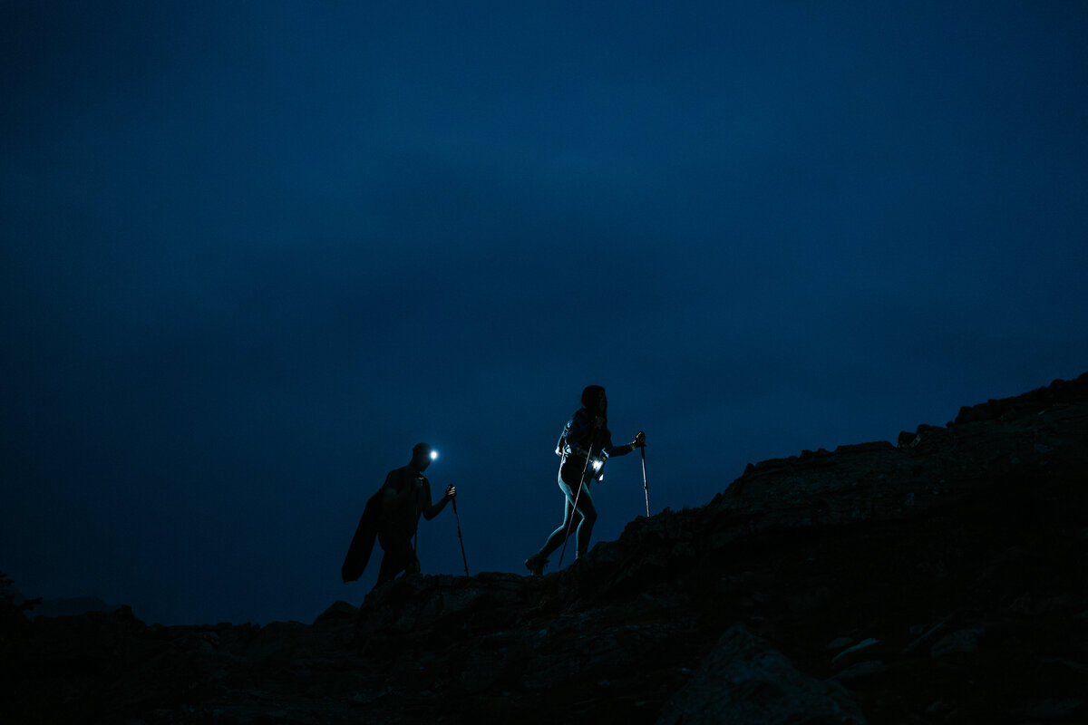Couple with headlamps hikes up the mountain in the dark during Kananaskis elopement