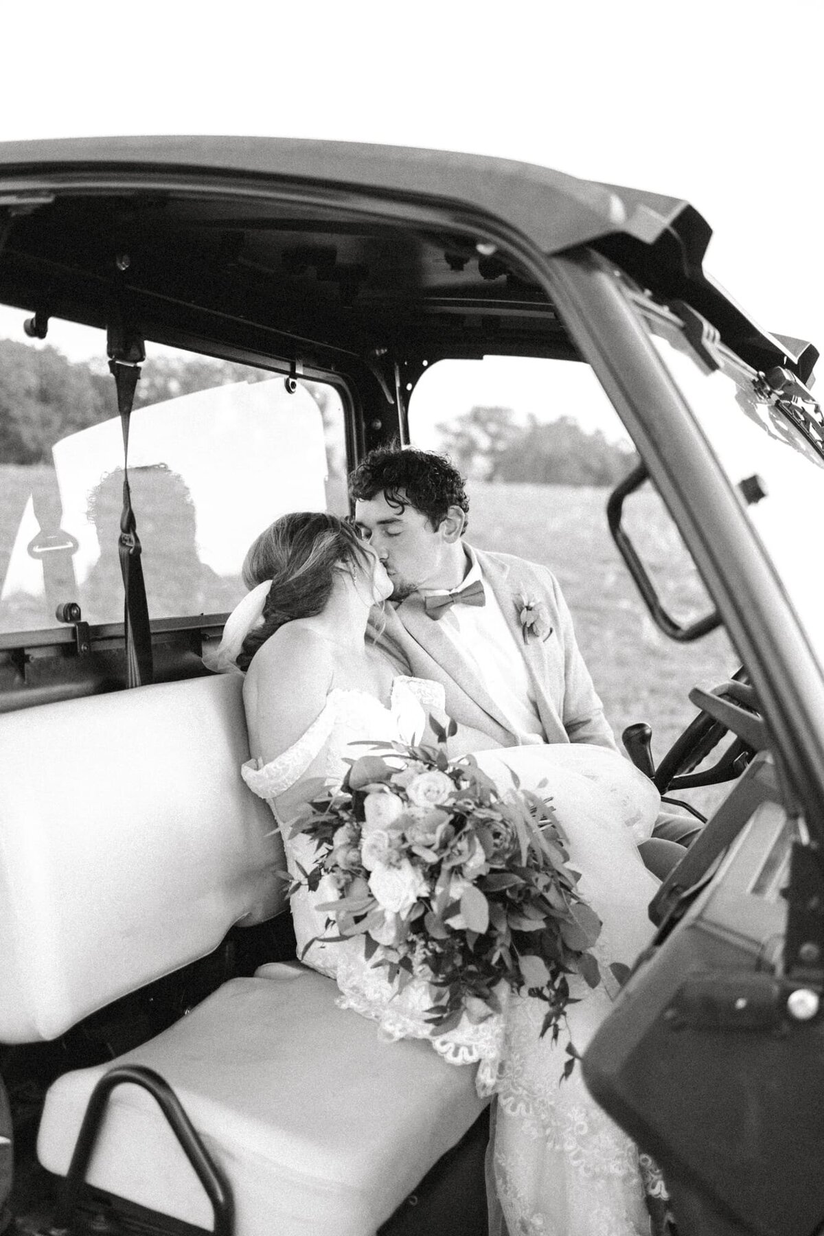 Bride leans in to kiss groom riding cart at farm wedding near Charlottesville VA