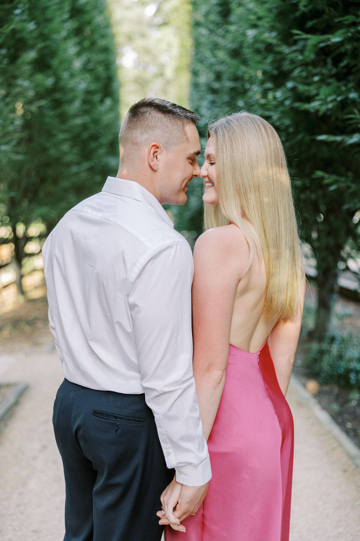 Engaged couple about to kiss on tree-lined path in Columbus park shot by Philadelphia photographer.