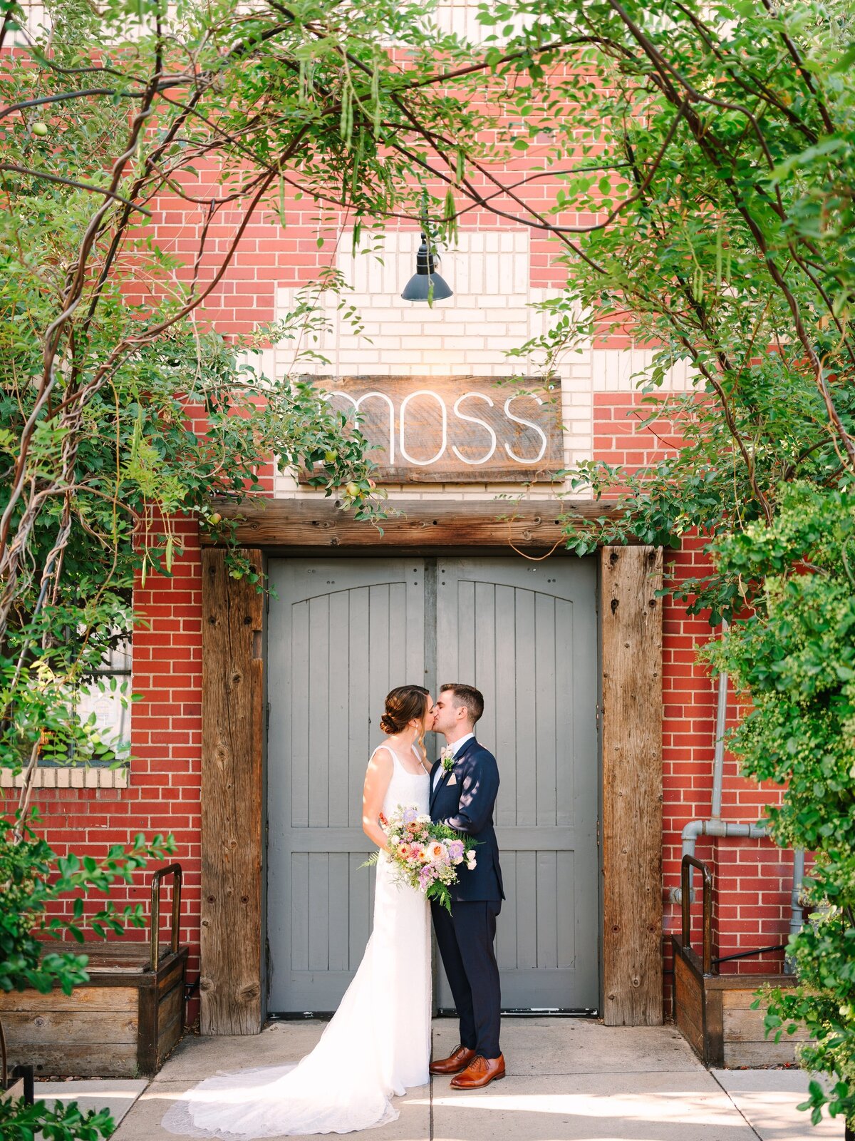 Bride and groom kiss outside of their wedding venue, Moss Denver.