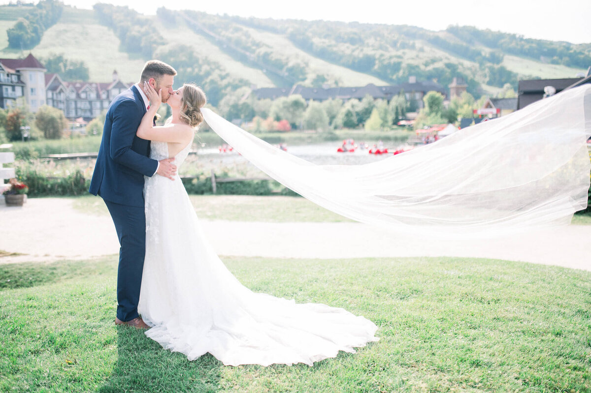 Bride and groom kissing with the long veil blowing in the wind captured by Toronto wedding photographer