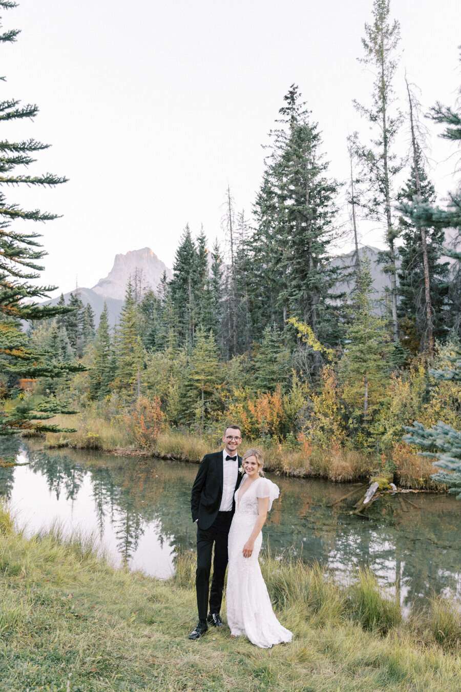 A bride and groom posing together by the river during their Calgary wedding reception