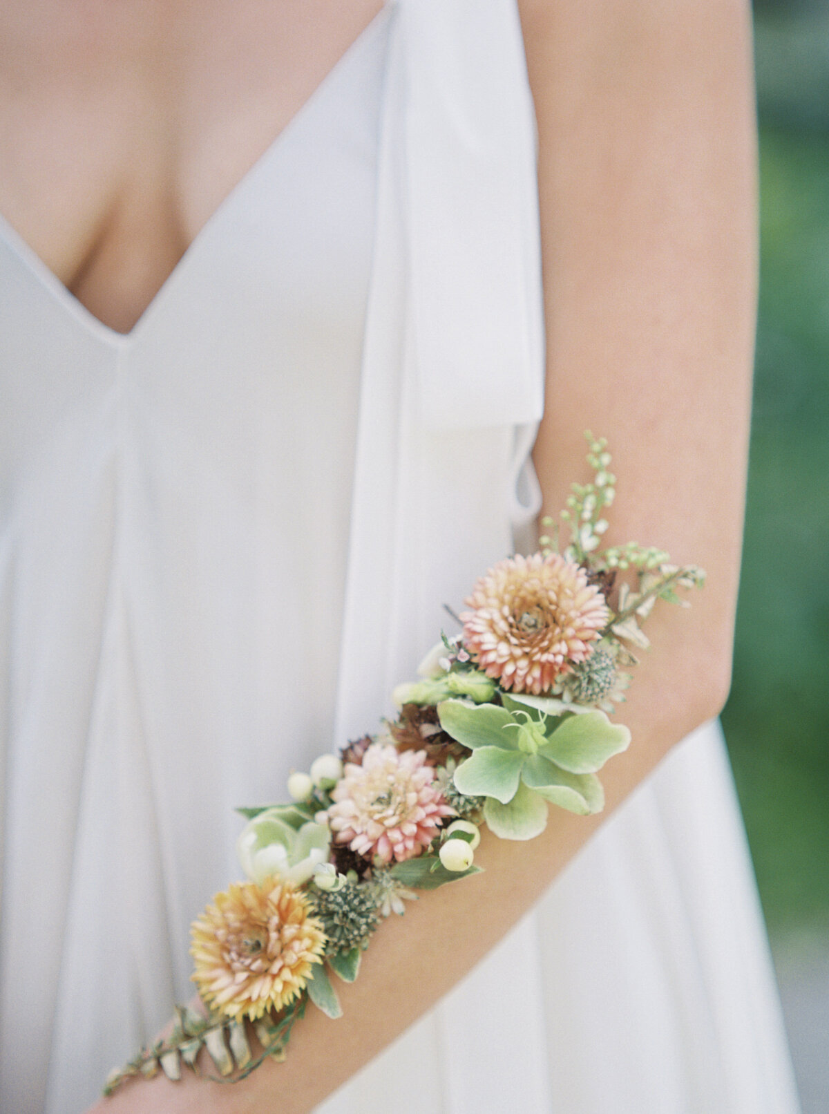 Flowers are delicately placed on a brides arm.