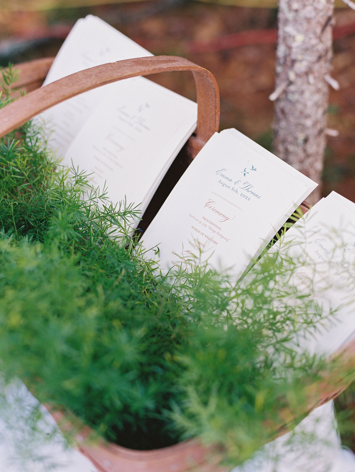 basket with greenery and wedding programs