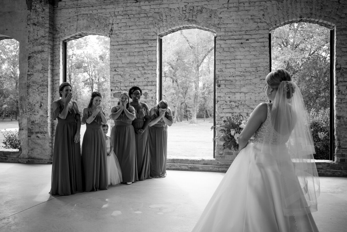 Bridesmaids reacting during bridesmaid first look at The Providence Cotton Mill by Charlotte wedding photographers DeLong Photography