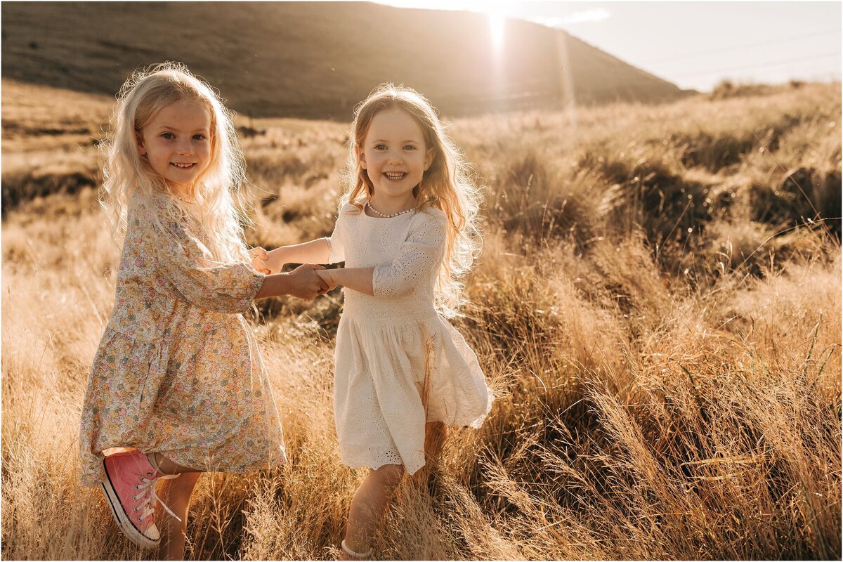 two girls in long dry grass port hills sunset family photographer christchurch