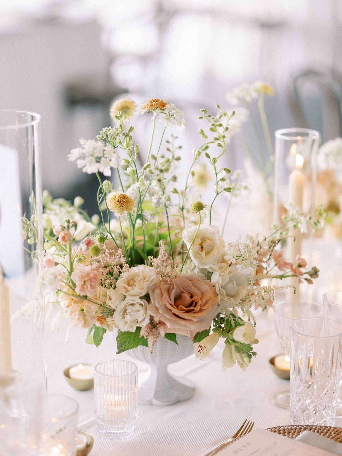A centrepiece of airy spring garden flowers and greenery at a Science Centre wedding reception.
