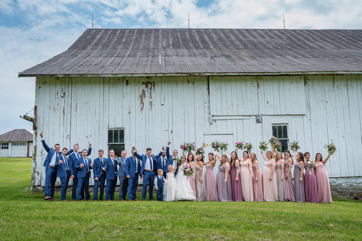 Wedding party standing by barn.