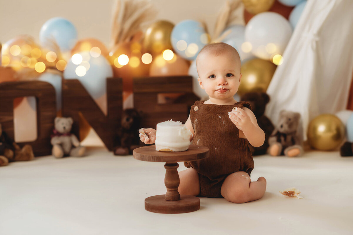Baby peers at the camera during his first birthday Cake Smash Photoshoot in Asheville, NC.