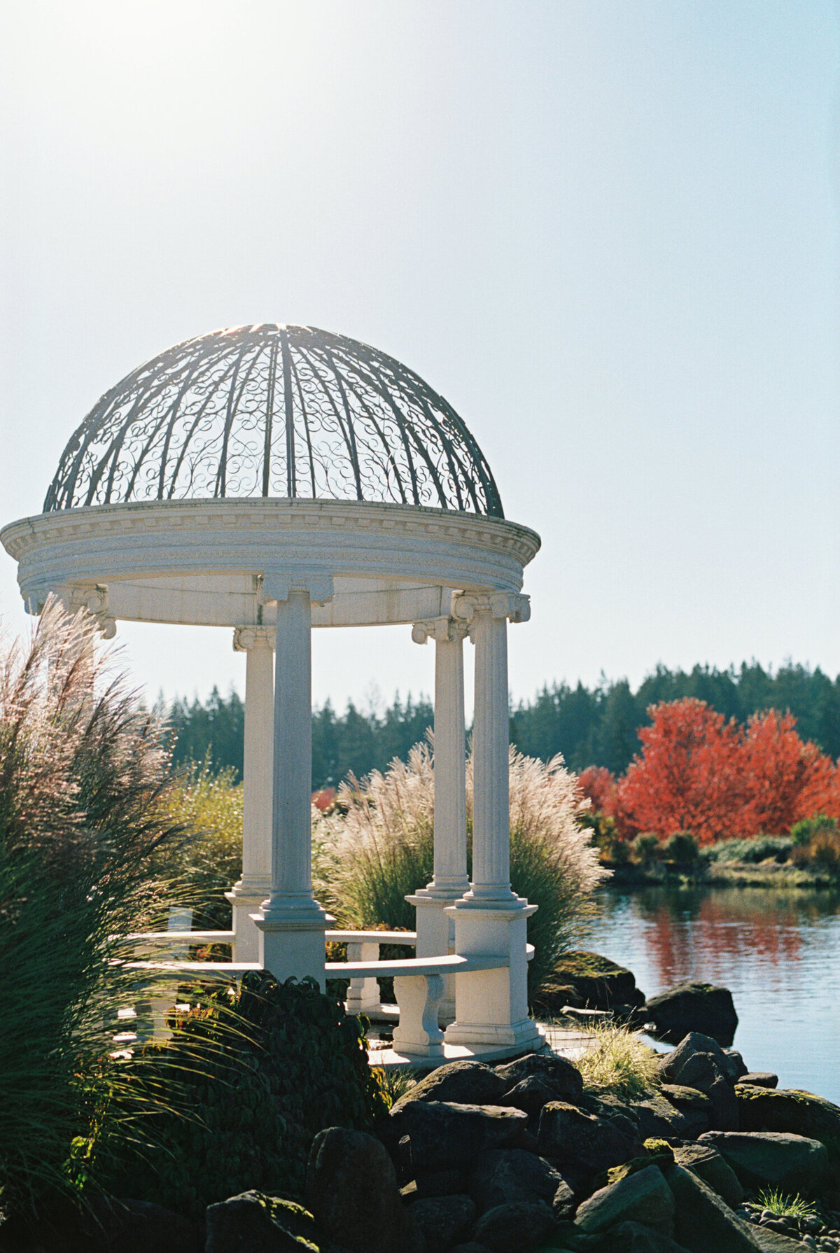 white gazebo overlooking lake at chateau de lis with bright fall colors