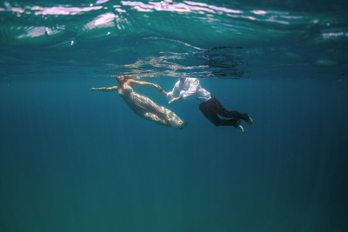 couple swimming in ocean in dress and clothes