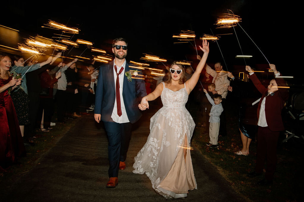 Bride wearing fun party glasses dancing with her partner under flashing lights during their nighttime wedding reception in New York City