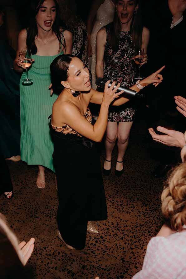 Female performer singing in a crowd of guests at an Australian function.
