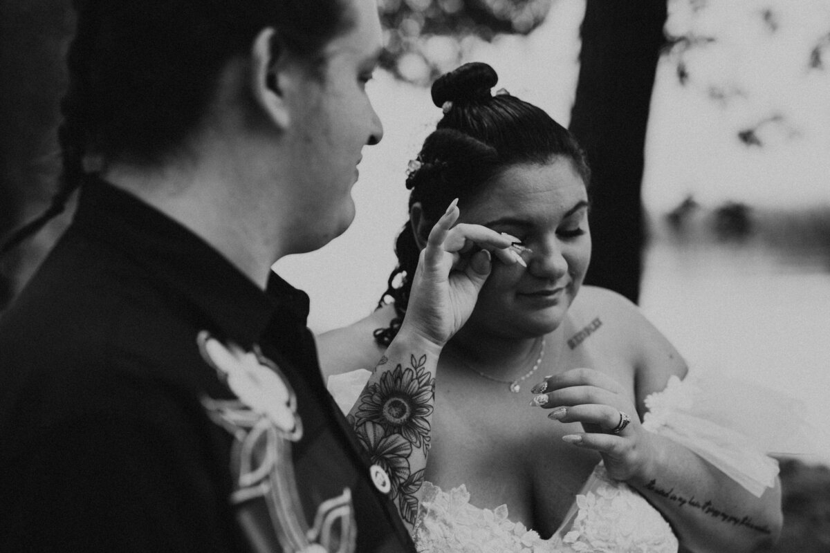 black and white candid as bride wipes away a tear and groom comforts her