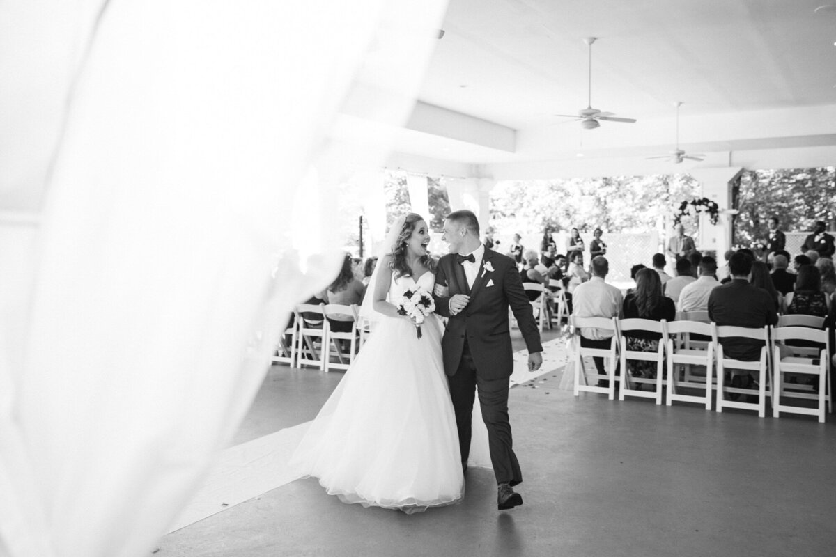Bride and groom looking at each other smiling walking down aisle after getting married