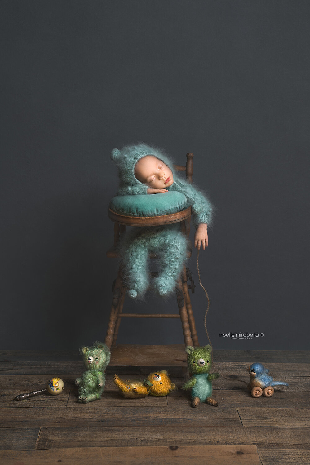 Newborn baby sleeping in vintage wooden high chair with vintage toys and vintage style bears.