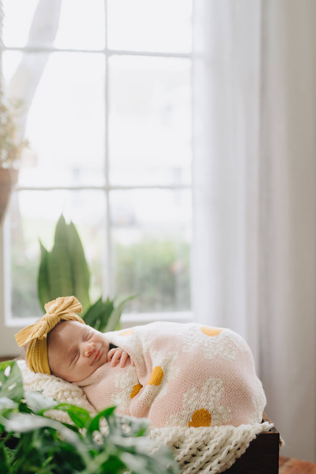 Baby wearing headband asleep in moses basket