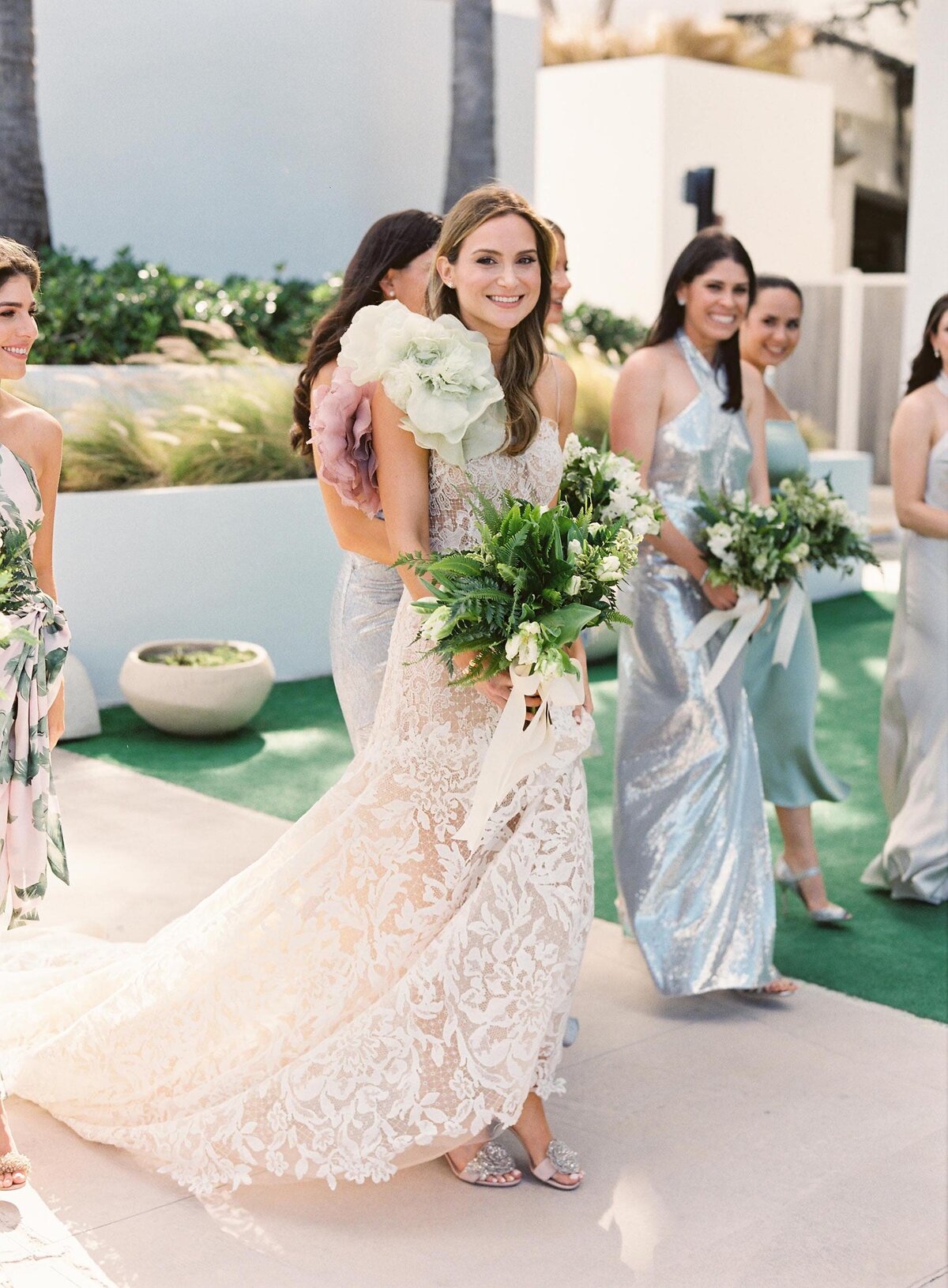 bride walking with bridesmaids in pastel dresses