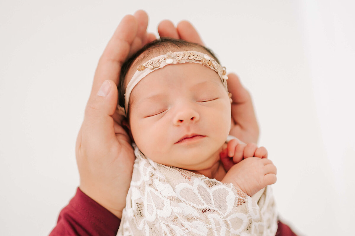 dad holding sleeping newborn in hands in Springfield MO newborn photography studio